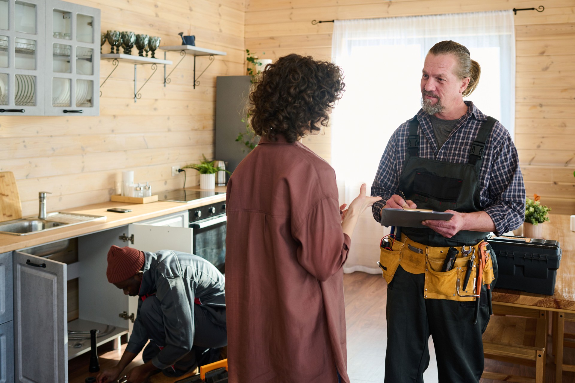Mature repairman making notes while listening to young housewife